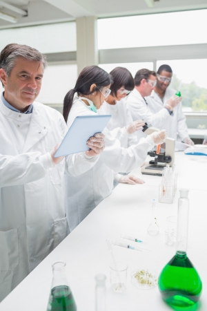 Happy chemist using tablet pc in busy labの写真素材