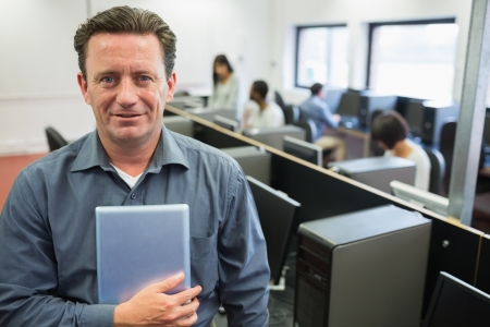 Man holding a tablet pc in computer room and smiling