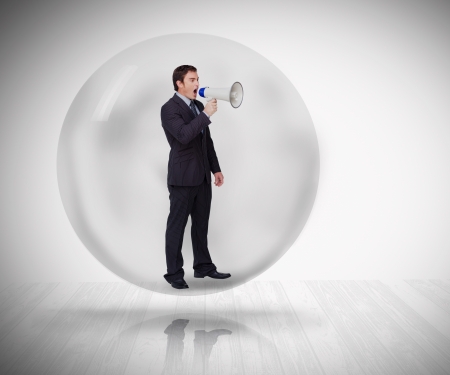 Businessman standing at a bubble holding a megaphoneの写真素材