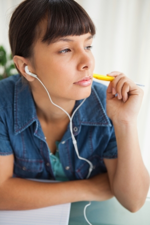 Female student devolved to do her homework while listening musicの写真素材