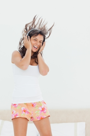 Student in pajama listing to music while jumping on her bed の写真素材