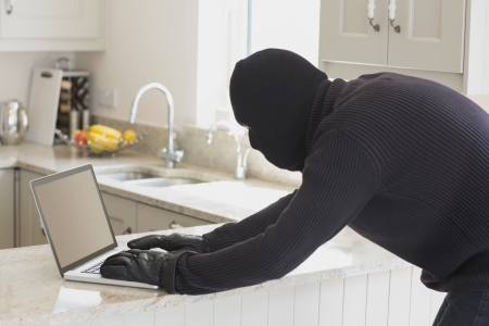 Robber using laptop in kitchen in unknown homeの写真素材