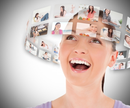 Woman viewing pictures around her head and smiling on grey backgroundの写真素材