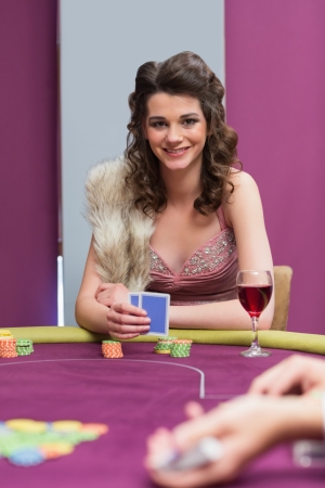 Woman sitting at the table smiling while holding cards in casinoの写真素材