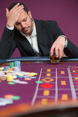 Man looking dejected at roulette table in casinoの写真素材