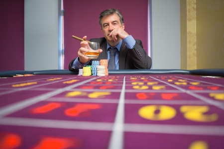 Man sitting at roulette table with cigar in casinoの写真素材