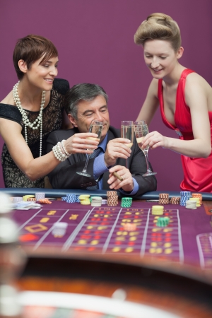 Women and man clinking glasses at the casinoの写真素材