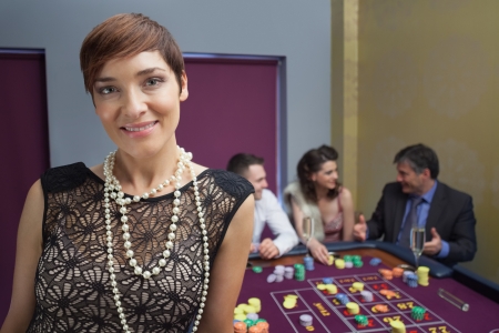 Woman smiling and standing at roulette table in casinoの写真素材