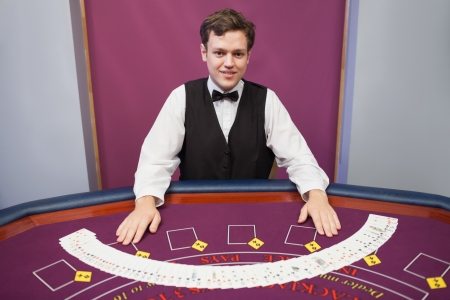 Smiling dealer with fanned out deck of cards in casino の写真素材