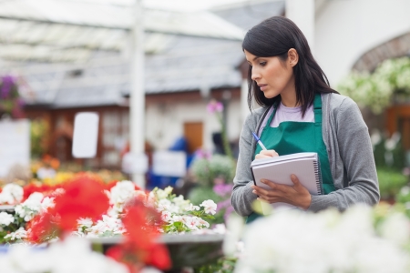 Worker taking notes while choosing a flower in the garden centreの写真素材