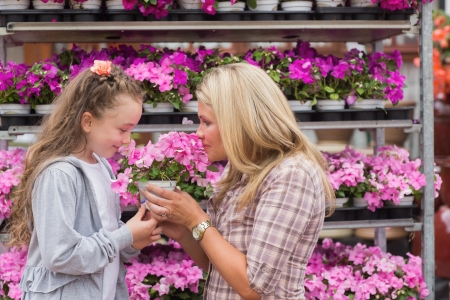 Maothe and daughter smelling plant in garden centerの写真素材