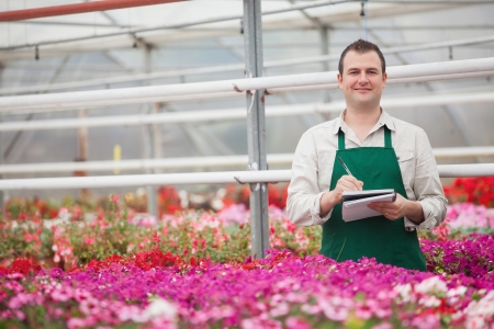 Smiling man taking notes in the greenhouse in garden centerの写真素材