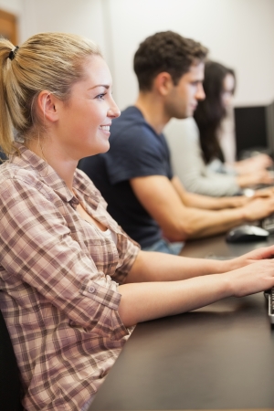 Woman sitting typing and smiling at computer classの写真素材