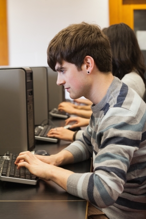 Man sitting at the tcomputer desk while typing in classの写真素材