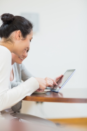 Students looking at tablet pc and smiling in collegeの写真素材