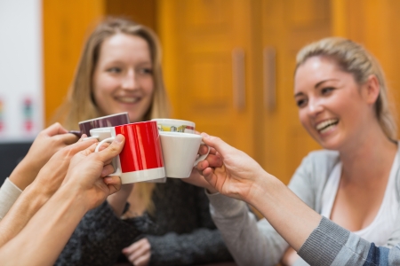 Students clinking cups while smiling in collegeの写真素材