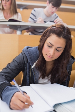 Woman sitting at the lecture hall while writingの写真素材