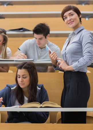 Students working while teacher smiling at the lecture hall の写真素材