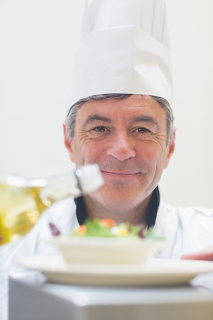 Chef preparing a salad with oil in the kitchenの写真素材