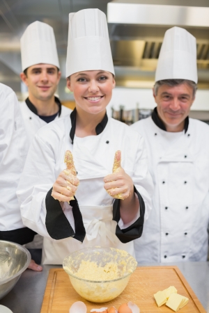 Baker giving thumbs up covered in dough with her classの写真素材