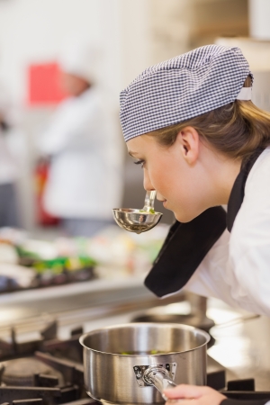 Chef smelling her soup on the stove in the kitchenの写真素材