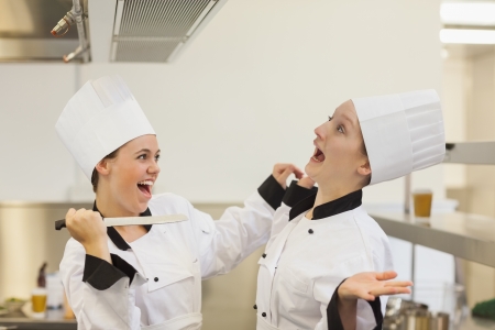 Two Chef's joking and having fun in the kitchen with a knifeの写真素材