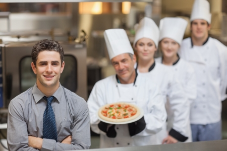 Waiter standing in front of Chef's holding a pizzaの写真素材