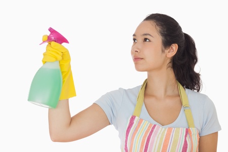 Young woman spraying cleaner in rubber gloves and apronの写真素材