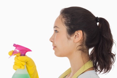 Brunette woman in rubber gloves spraying cleaning productの写真素材