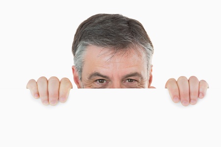 Man hiding behind white board and peeking overの写真素材