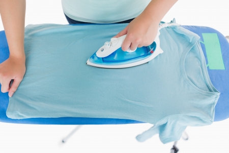 Woman ironing a t shirt on an ironing tableの写真素材
