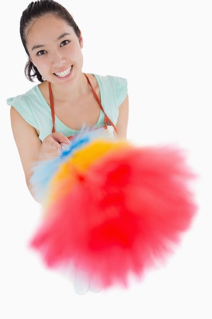Happy woman holding a duster in the air on a white backgroundの写真素材