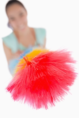 Woman pointing a duster at the camera on a white backgroundの写真素材