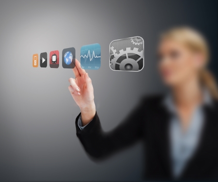 Businesswoman selecting application from hologram interface against grey backgroundの写真素材