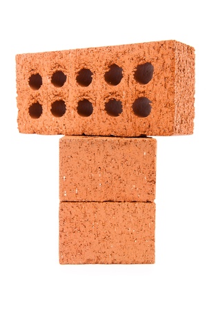 Three clay bricks with holes being stacked against a white backgroundの写真素材