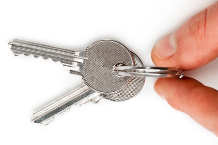 Finger holding set of keys against white background