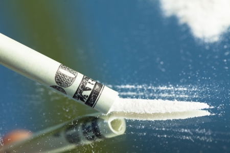 Snorting a line of drugs with a rolld up dollar bill on a mirrorの写真素材