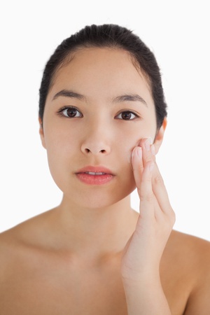 Black haired woman touching her face on white backgroundの写真素材