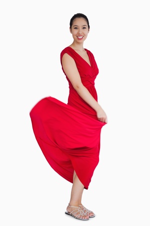 Smiling woman with red dress blowing up の写真素材