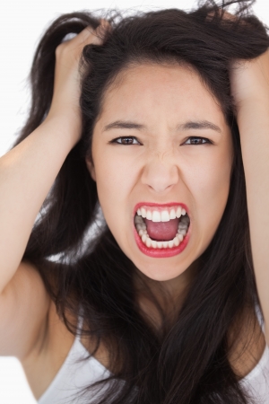 Woman screaming and pulling her hair out on white backgroundの写真素材
