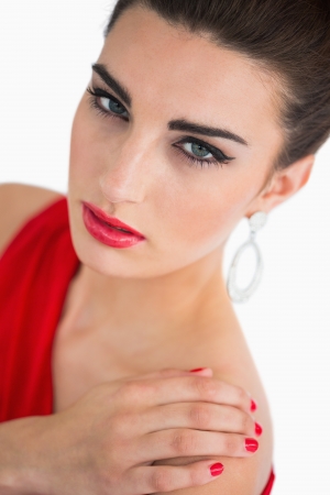Glamorous brunette looking serious while touching her shoulderの写真素材