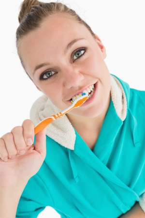 Woman with bathrobe washing her teeth in the white backgroundの写真素材