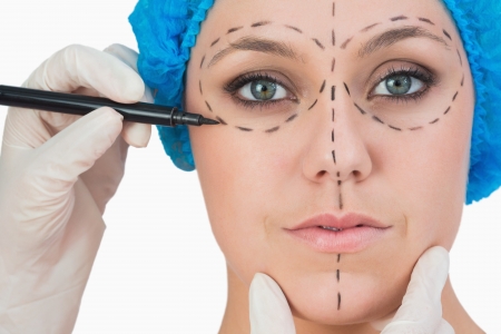 Plastic surgeon drawing on woman's face for face liftの写真素材