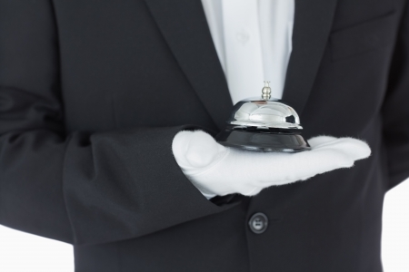 Man holding a hotel bell in his hand in front of cameraの写真素材