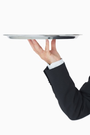 Well-dressed man holding silver tray on white backgroudの写真素材