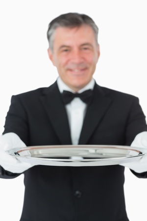 Waiter looking at the camera while holding a silver tray on white backgroundの写真素材