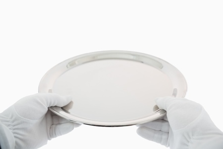 Gloved hands holding out large silver trayの写真素材