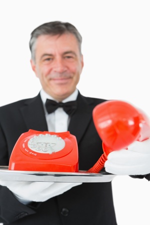 Waiter passing the red phone receiver on a silver tray