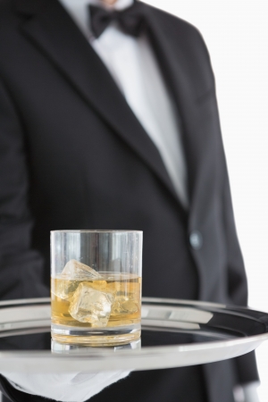 Man holding silver tray with whiskey glassの写真素材