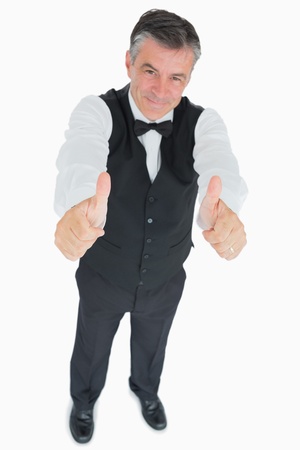 Smiling waiter in suit showing thumbs upの写真素材
